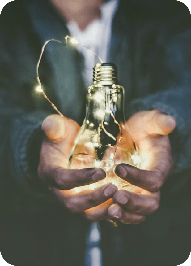 Hands holding an illuminated light bulb, a metaphor for catching costly bugs before production